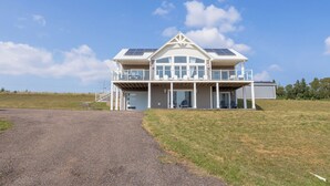 A modern two-story house with a covered porch, large windows, and solar panels on the roof.