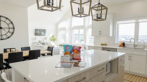 A modern kitchen with a large island, white cabinetry, and pendant lighting.