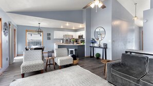 Un vaste espace de vie comprenant une cuisine moderne, un ventilateur de plafond et un coin repas avec vue.