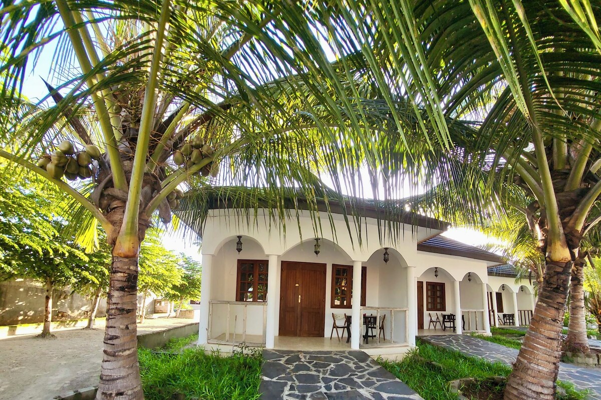 A building with a stone pathway leading to a covered porch with outdoor seating.