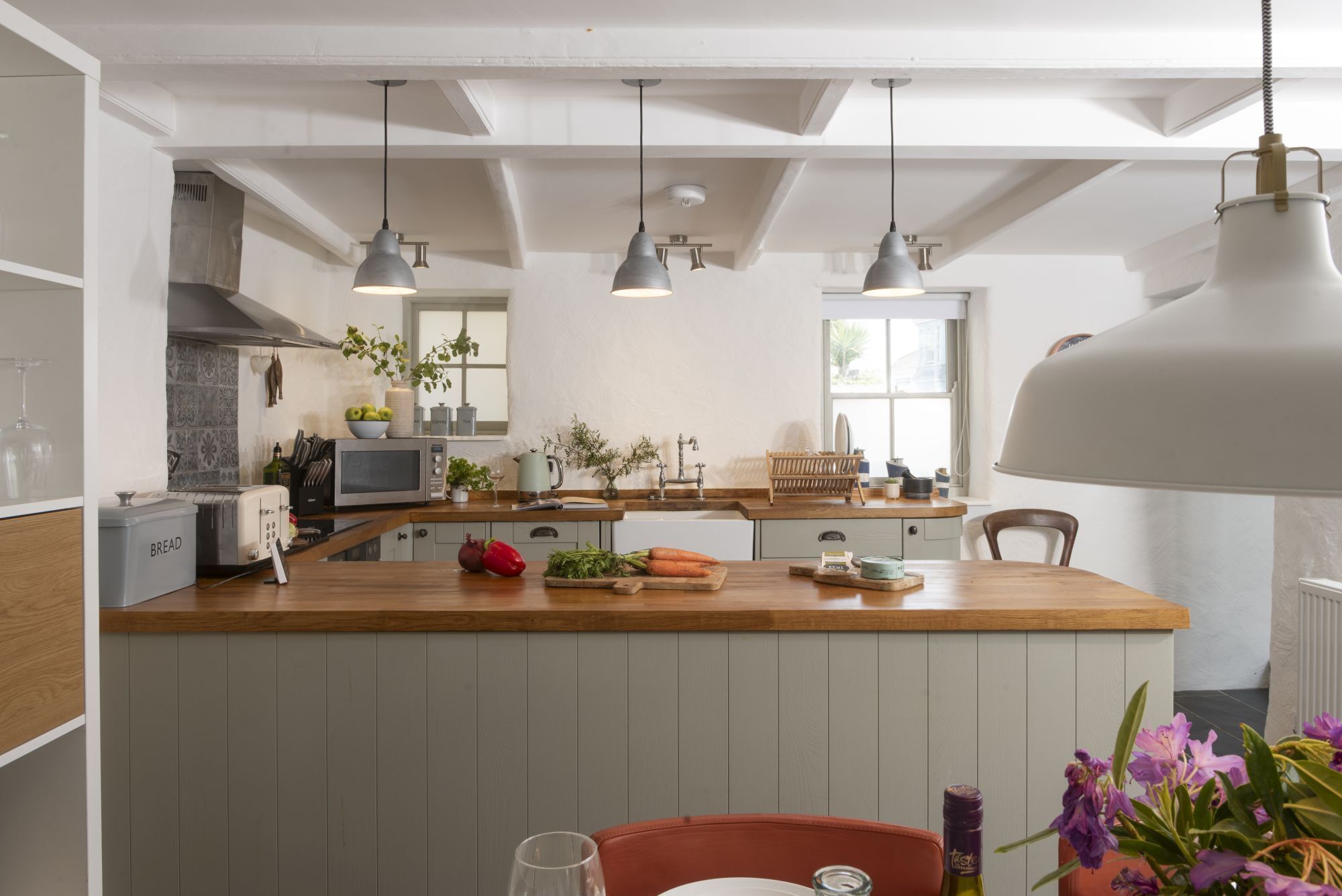 Una cocina moderna con una isla de madera, luces colgantes y vistas a la ciudad.