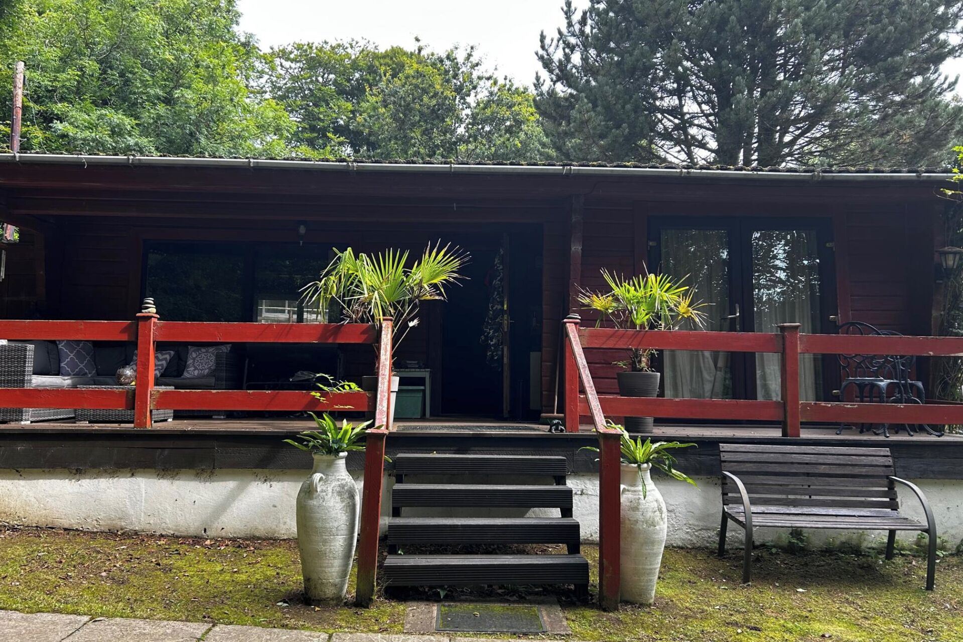 A building with a red railing, a bench, and potted plants.