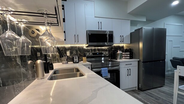 A modern kitchen with white cabinets, stainless steel appliances, and pendant lights.
