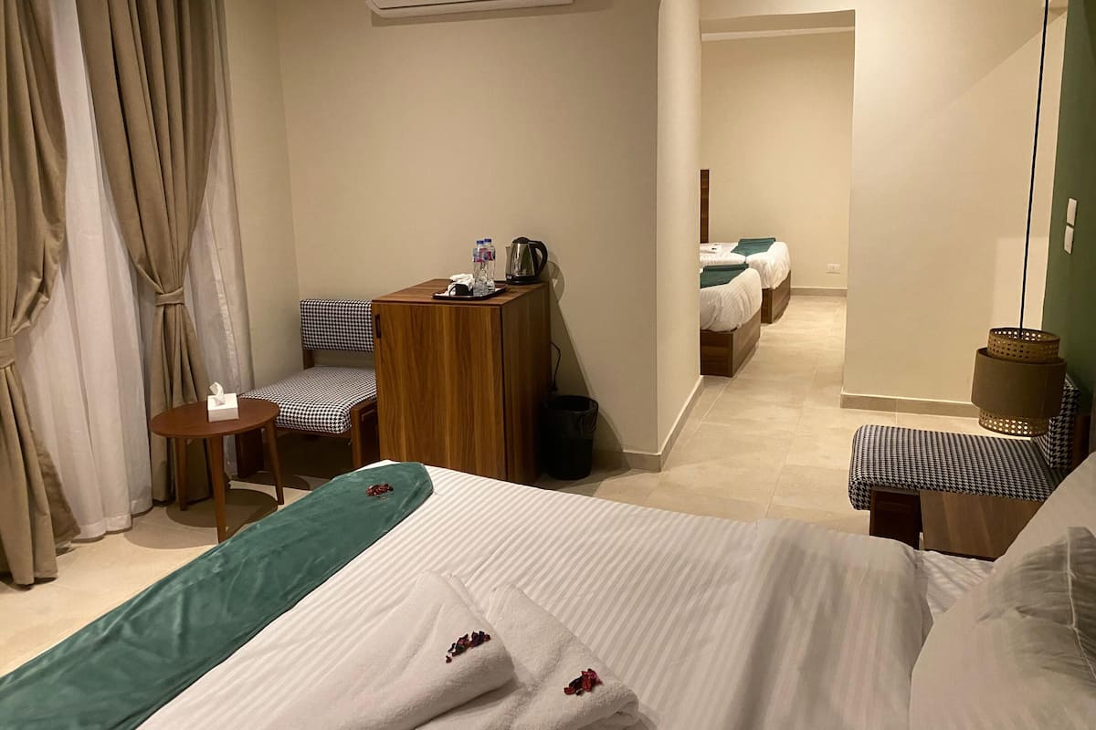 Habitación de hotel con cama, escritorio, silla, una mesita y baño visible a través de una puerta abierta.