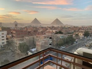Un paisaje urbano con pirámides al fondo, una calle concurrida y edificios en primer plano.