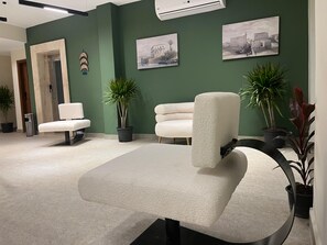 A modern waiting area with green walls, two white armchairs, and potted plants. - The Nomad Pyramids Boutique Hotel (Giza)