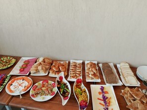 Une table garnie de différents plats et de pain, probablement pour un buffet ou un repas partagé.