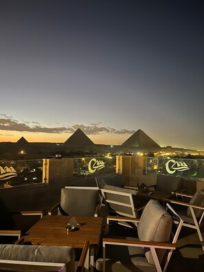 Une terrasse sur le toit, aménagée avec des sièges, d’où l’on peut admirer les pyramides au crépuscule.