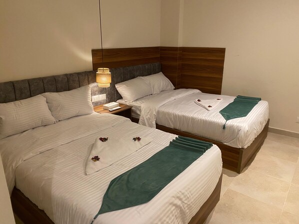 A hotel room with two beds, a nightstand with a lamp, and a wooden headboard. - The Nomad Pyramids Boutique Hotel (Giza)