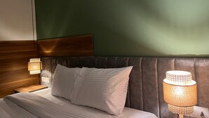 A hotel room with a bed, a nightstand, a lamp, and a wooden headboard. - The Nomad Pyramids Boutique Hotel (Giza)