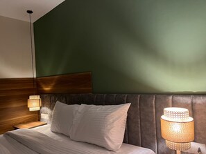 A hotel room with a bed, a nightstand, a lamp, and a wooden headboard. - The Nomad Pyramids Boutique Hotel (Giza)