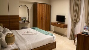 A hotel room with a bed, a TV, a wardrobe, and a desk with a mirror. - The Nomad Pyramids Boutique Hotel (Giza)