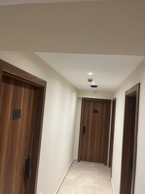 A hallway with wooden doors, a ceiling light, and a security camera. - The Nomad Pyramids Boutique Hotel (Giza)