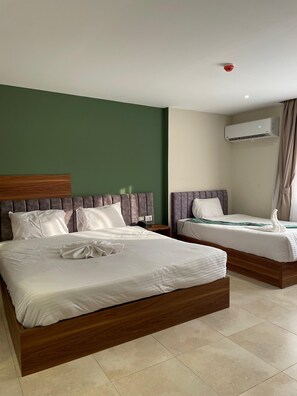 A hotel room with two beds, a green wall, an air conditioning unit, and a ceiling-mounted smoke detector. - The Nomad Pyramids Boutique Hotel (Giza)