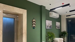 Eine moderne Lobby mit grüner Wand, einer Rezeption, einer Sitzecke und einem Aufzug.