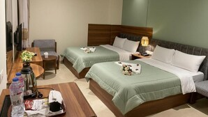 A hotel room with two beds, a desk, a chair, a TV, and an air conditioning unit. - The Nomad Pyramids Boutique Hotel (Giza)