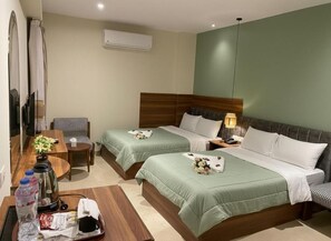 A hotel room with two beds, a desk, a chair, a TV, and an air conditioning unit. - The Nomad Pyramids Boutique Hotel (Giza)