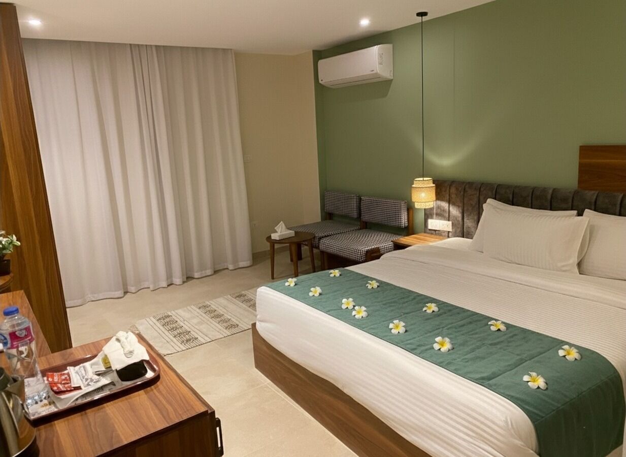 Une chambre d’hôtel comprenant un lit, un bureau, une chaise, une table de chevet, un climatiseur et une fenêtre avec des rideaux.