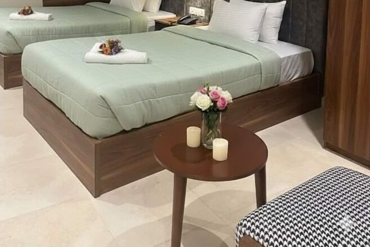 Habitación de hotel con dos camas, una mesita redonda con velas y un cabecero de madera.
