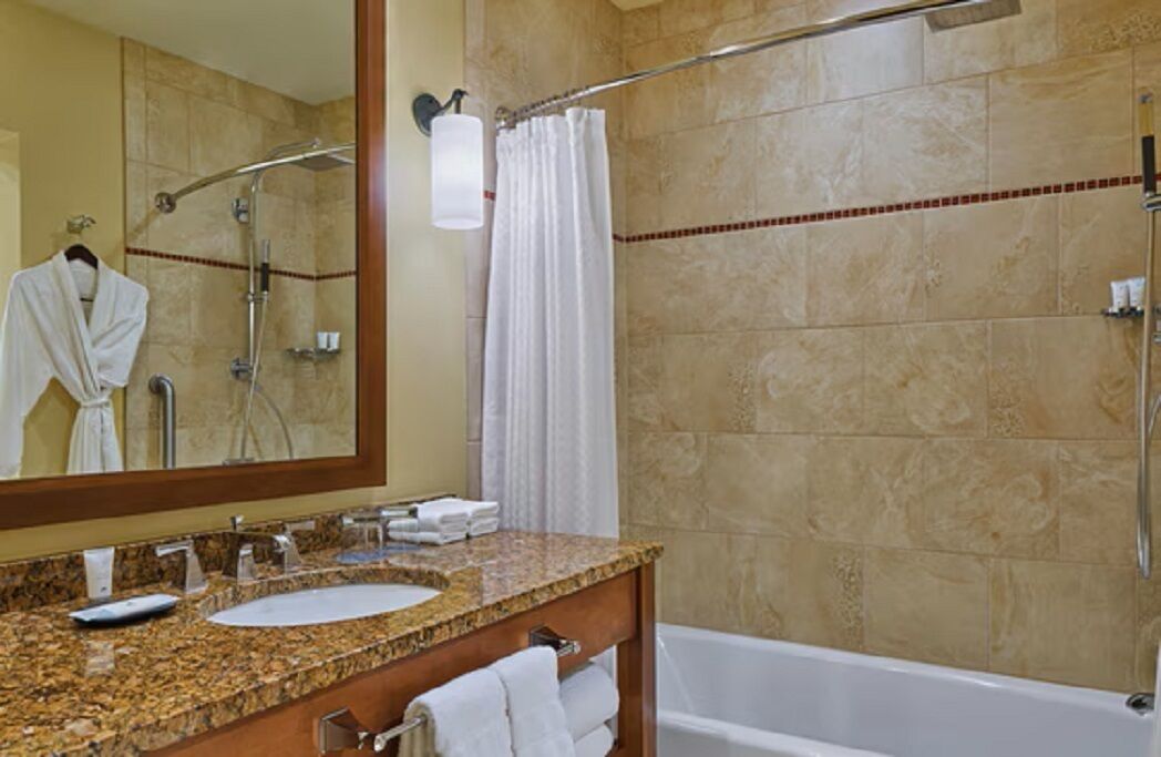 A bathroom with a granite countertop sink, a mirror, a shower with a glass door, and a bathtub.