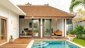 Une maison moderne dotée d’une piscine, de portes-fenêtres coulissantes et d’un patio aménagé avec du mobilier d’extérieur.