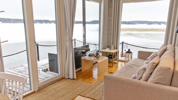 Una habitación acogedora con sofá, una mesita y una silla, con vistas a un paisaje nevado a través de amplios ventanales.