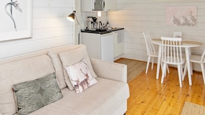 Un espacio de sala cómodo con un sofá, una mesa de comedor con sillas, una kitchenette y un cuadro en la pared.