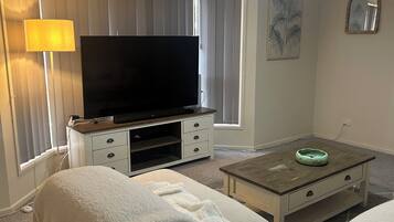 Relax in this stylish living room with a large sofa, flat-screen TV, and cozy throw blanket.