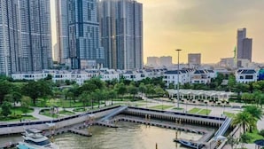 A marina with boats docked, surrounded by high-rise buildings and a park area. - Vinhomes Central Park-Premier Apartments (Ho Chi Minh City)