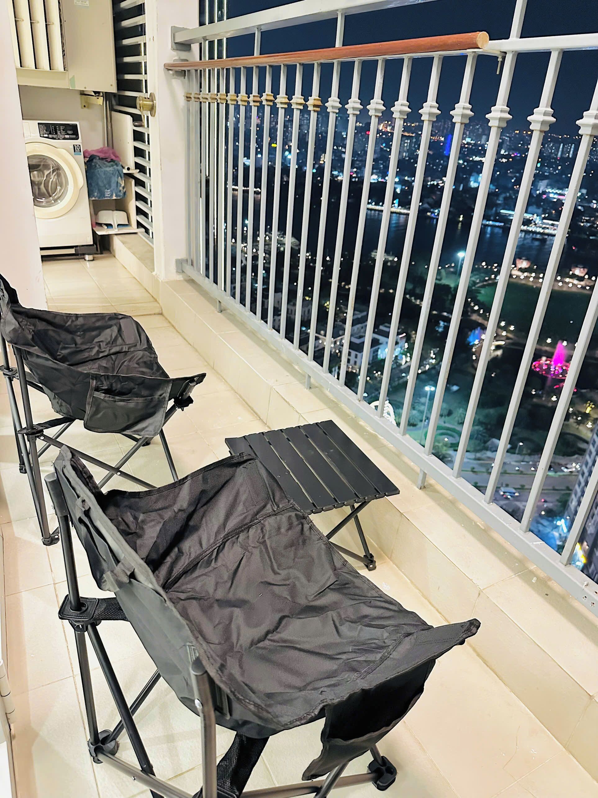 A balcony with a metal railing and a view of a cityscape at night.