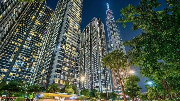 A high-rise building complex with multiple floors, large windows, and a prominent tower with illuminated stripes. - Vinhomes Central Park-Premier Apartments (Ho Chi Minh City)