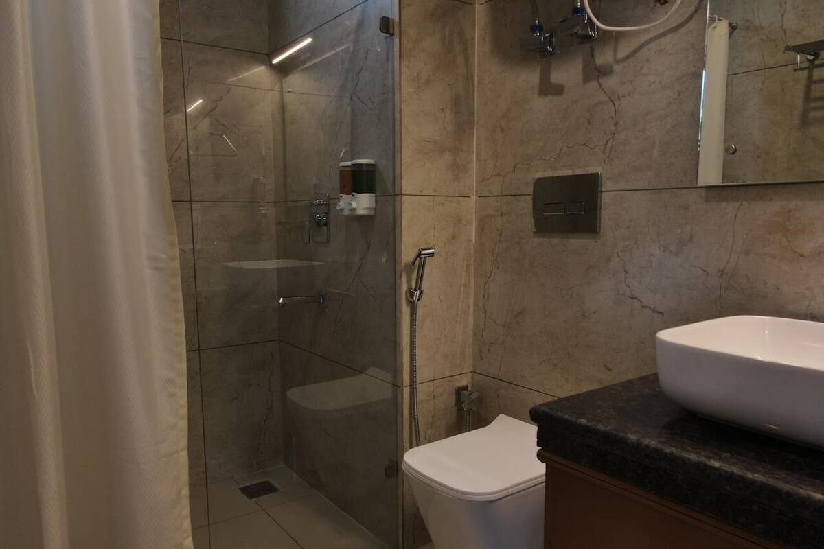 Een moderne badkamer met een douchekabinet van glas, een wit toilet en een groot wastafel.