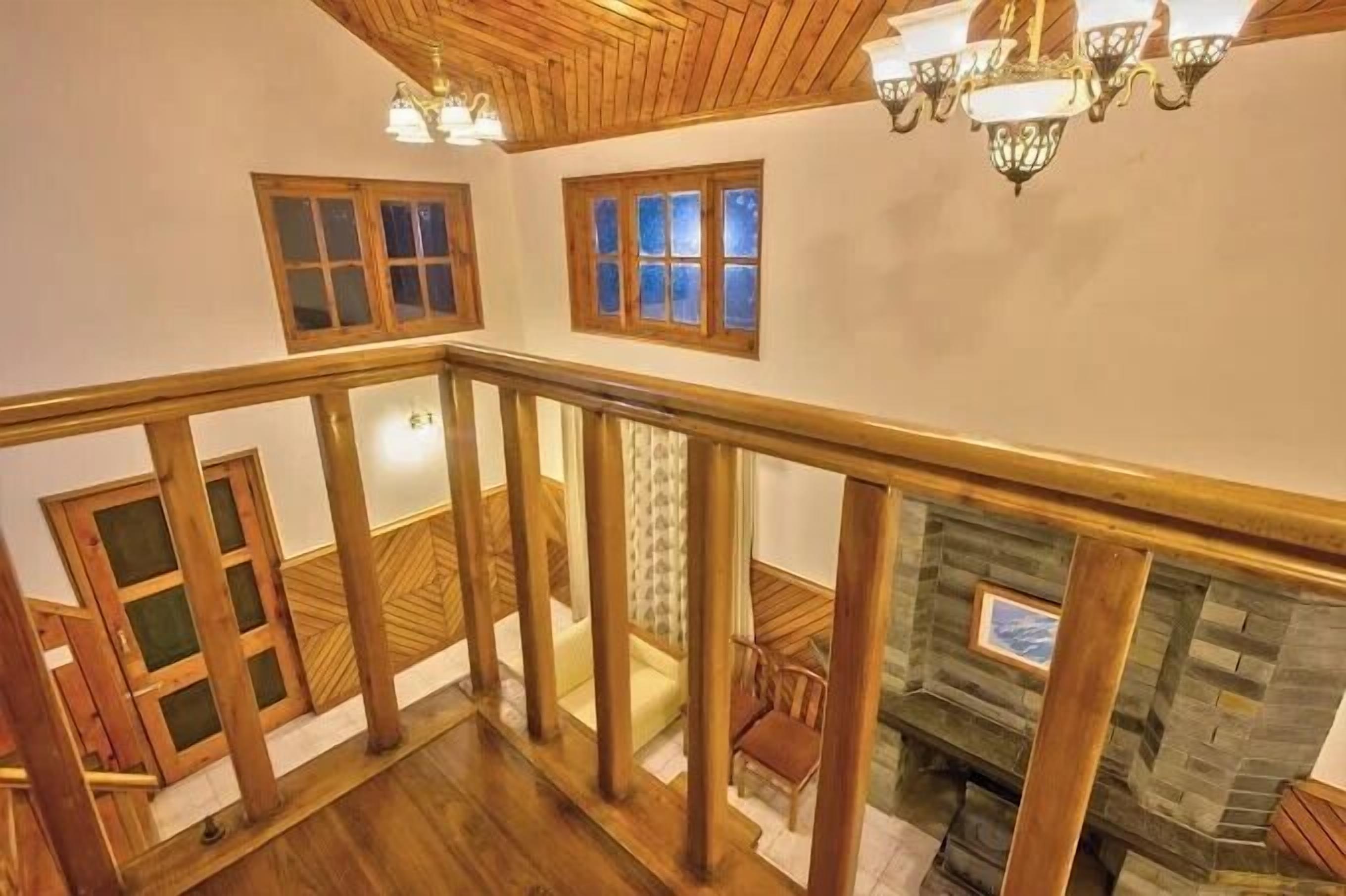 A wooden staircase with a railing leading to a second-floor area with a fireplace and a view of the lower floor.