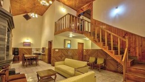 A spacious living area with a wooden staircase, a sofa, and a dining table. - Snow Park Villas & Resort Manali (Manali)