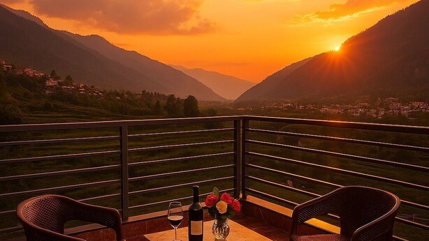 A terrace with a table and chairs, a bottle of wine, and a vase of flowers, overlooking a mountainous landscape during sunset. - Snow Park Villas & Resort Manali (Manali)