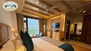 A hotel room with a large bed, a desk, a TV, and a view of the outdoors. - Snow Park Villas & Resort Manali (Manali)