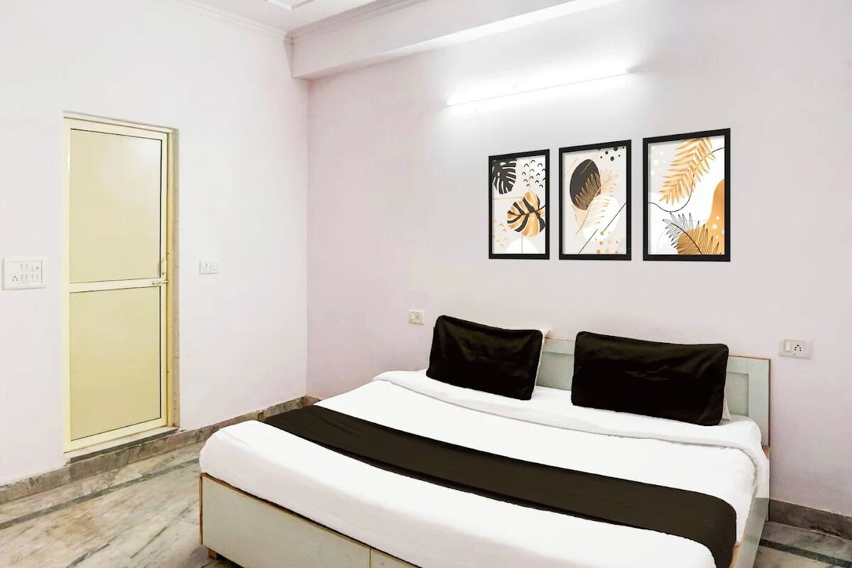 Ein Schlafzimmer mit einem Bett, einer Tür und drei gerahmten Kunstwerken an der Wand.