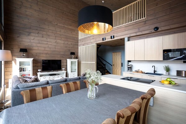 Een moderne keuken met een eethoek, houten wanden en een trap naar een hoger gelegen niveau.