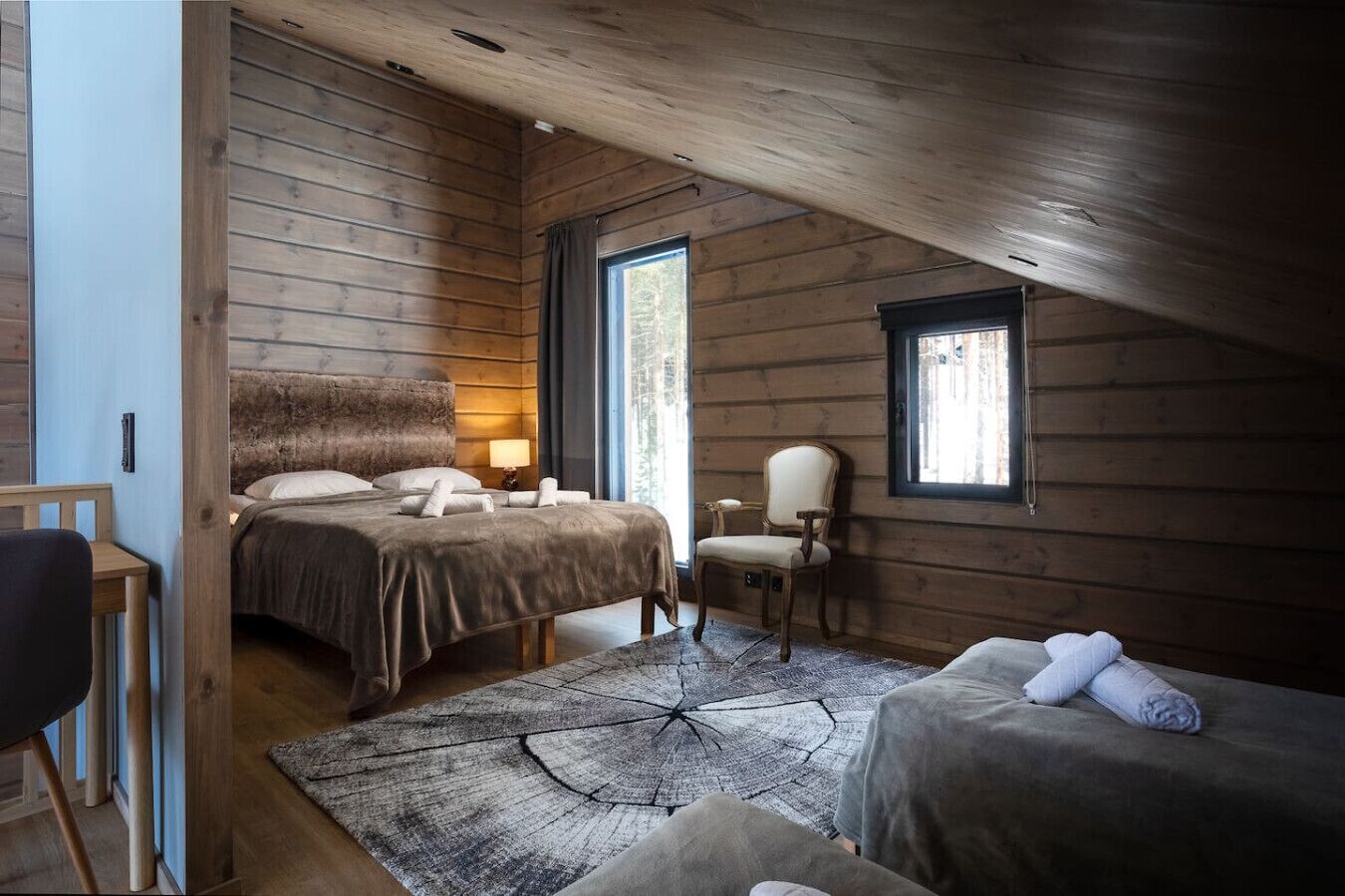 A cozy cabin room with a bed, a chair, and a small table.