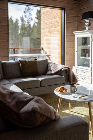 Een moderne woonkamer met een grijze bank, een salontafel met gebakjes en een witte kast met boeken.