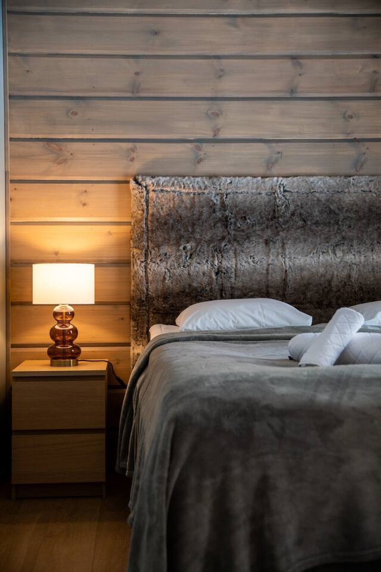 Ein Schlafzimmer mit hölzernem Kopfteil, einem Nachttisch mit Lampe und einem Bett mit weißer Bettwäsche.