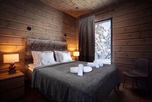 A wooden-paneled room with a bed, nightstands, and a window with curtains.