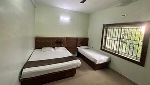A bedroom with a large bed, a smaller bed, a ceiling fan, and a window with bars. - Bms Luxury homes (Anekal)