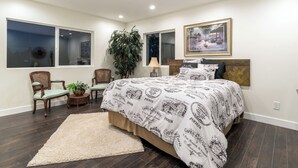 Un dormitorio con una cama grande, una ventana, una planta en maceta y un cuadro en la pared.