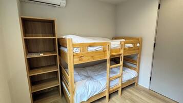A bunk bed with a wooden frame, a built-in shelf unit, and a white air conditioning unit mounted on the wall.