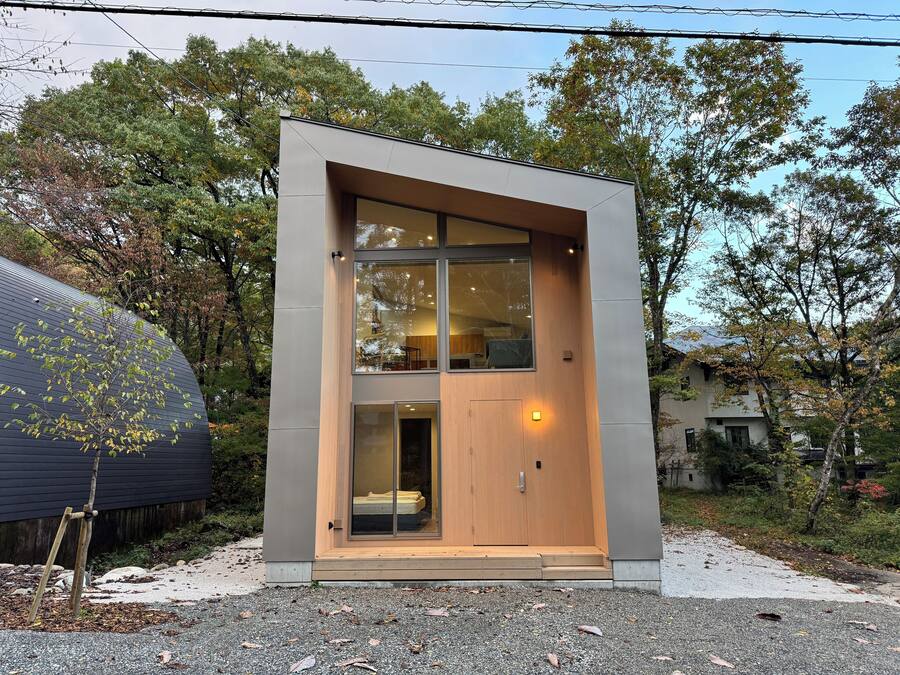 Un edificio moderno de dos pisos con un ventanal grande y una puerta de madera.