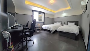 Een hotelkamer met een bureau, twee bedden, een stoel en een spiegel.