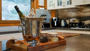 Una cocina con un recipiente metálico grande que contiene una botella, una bandeja de madera y un vaso pequeño.