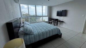 Ein modernes Schlafzimmer mit einem großen Bett, einem Schreibtisch und einem Fernseher.