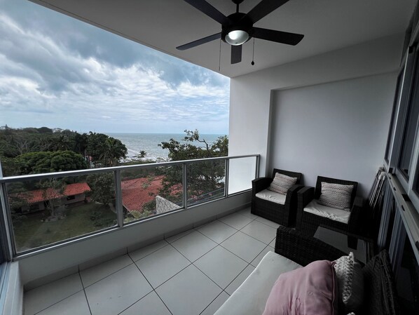 Ein Balkon mit Meerblick und Deckenventilator.
